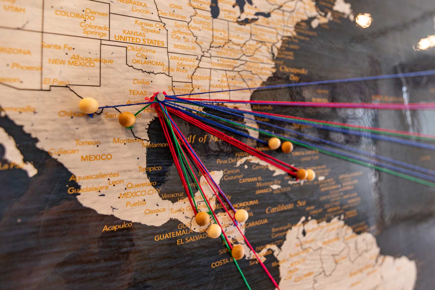 A pin in a United States map on College Station withs strings connected to pins placed on various countries.