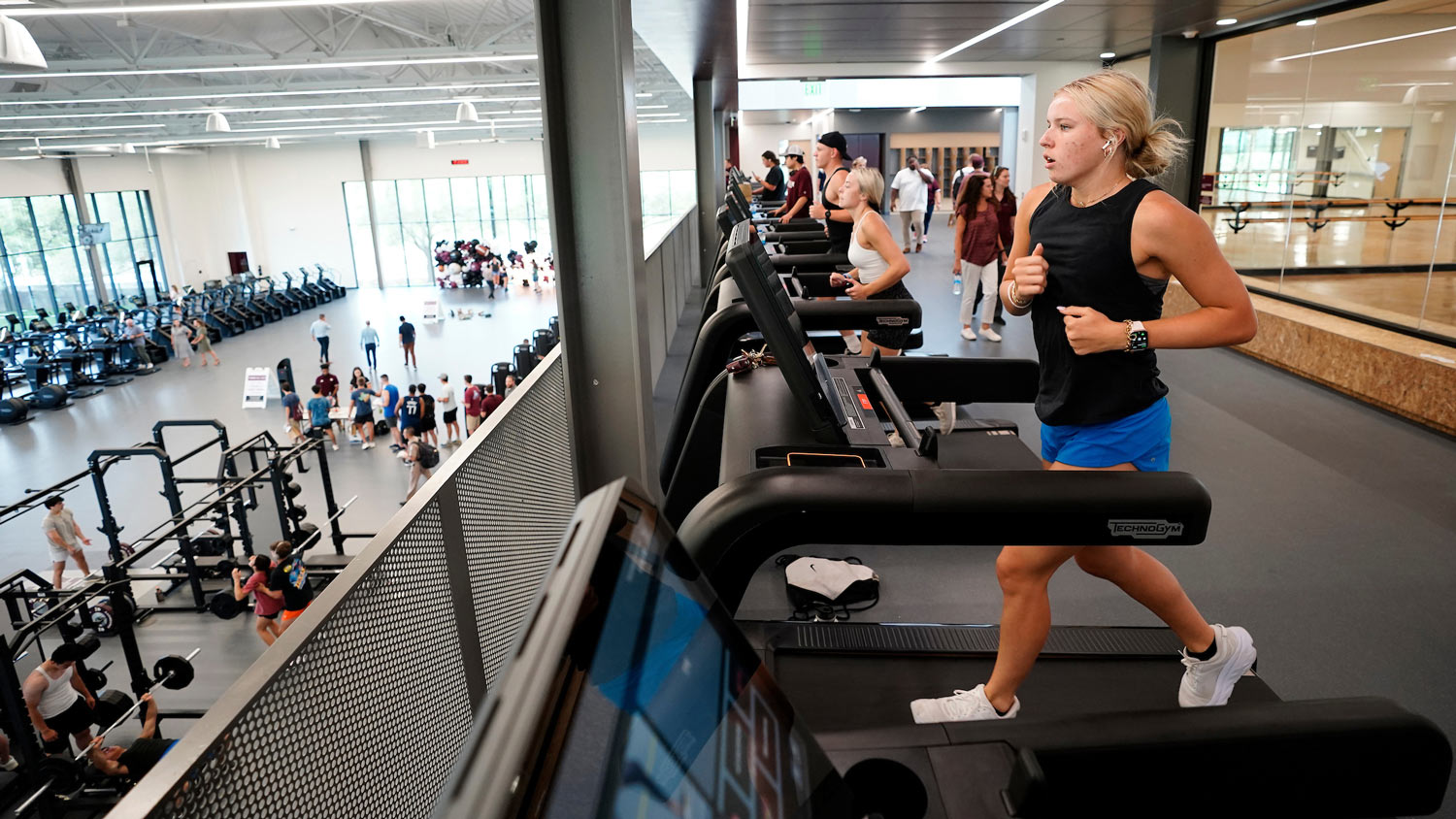 A student runs on a treadmill overlooking the weight lifting area on the first floor.