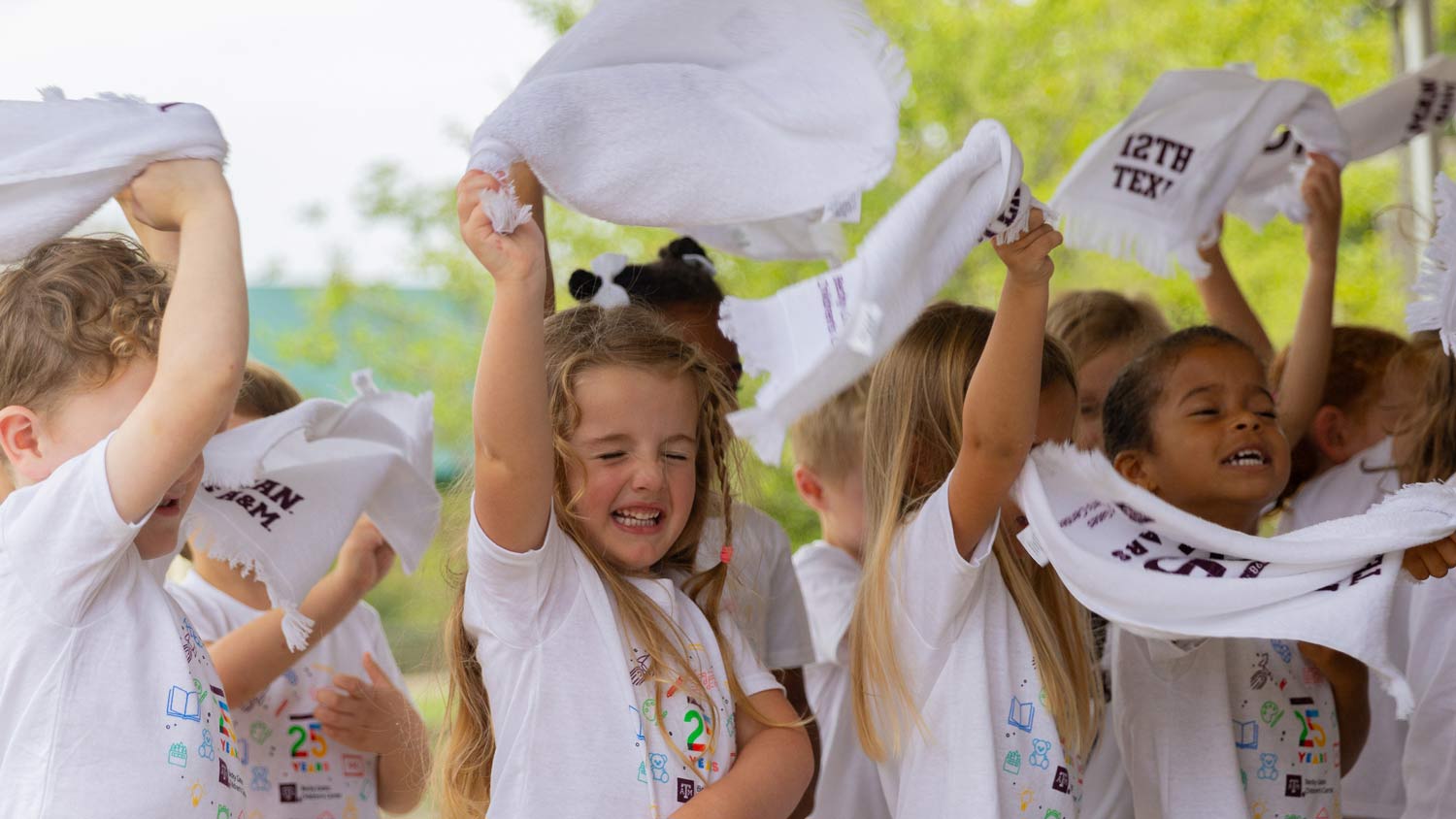 A group of pre-k student wave 12th man towels at a children's event
