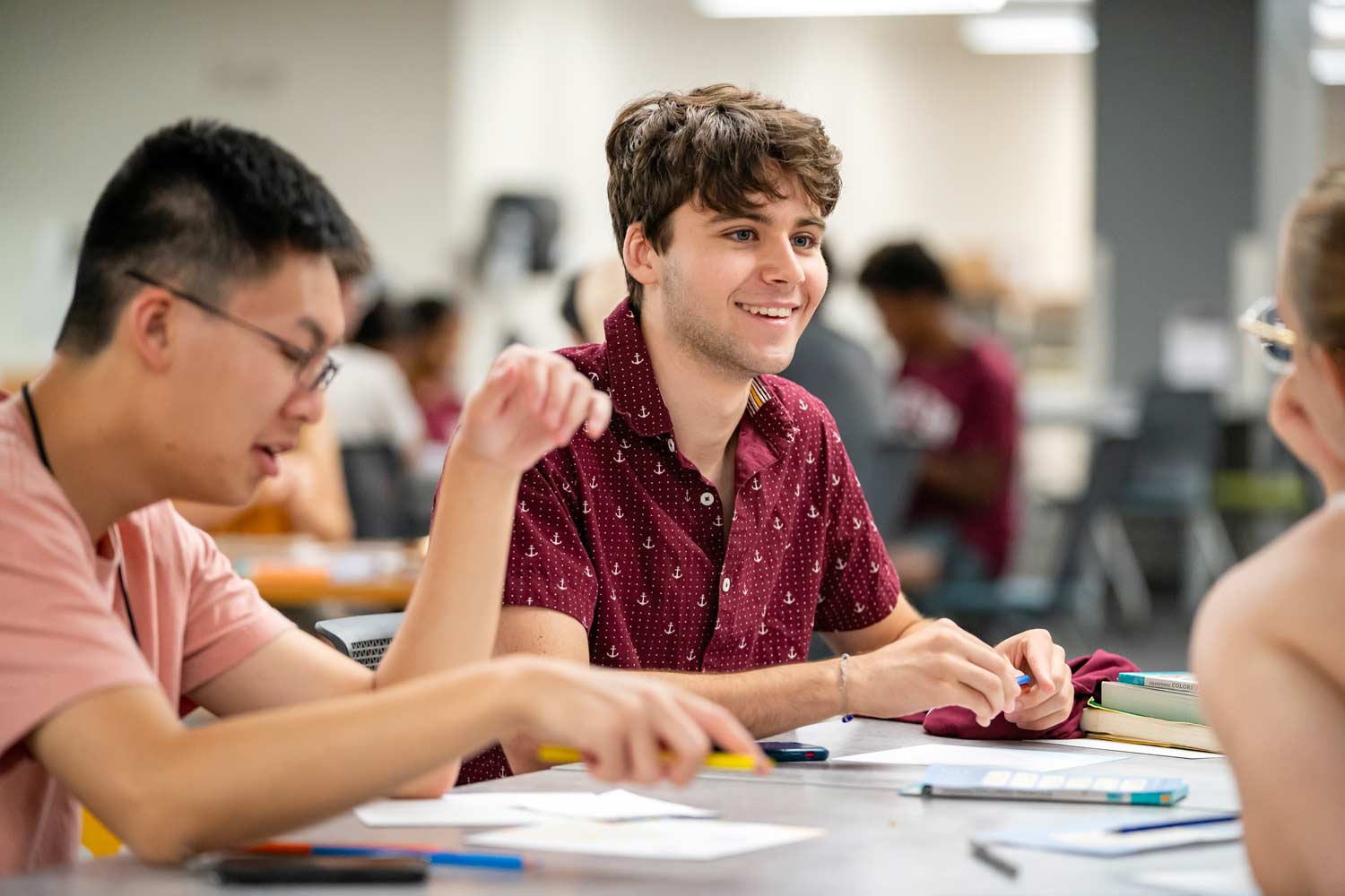 Texas A&M student smiling while sitting at a table in the library.