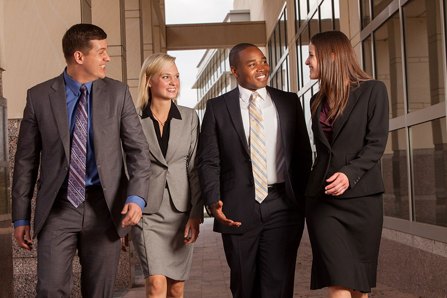 Bush School of Government and Public Service students, dressed in professional attire, walk together after class