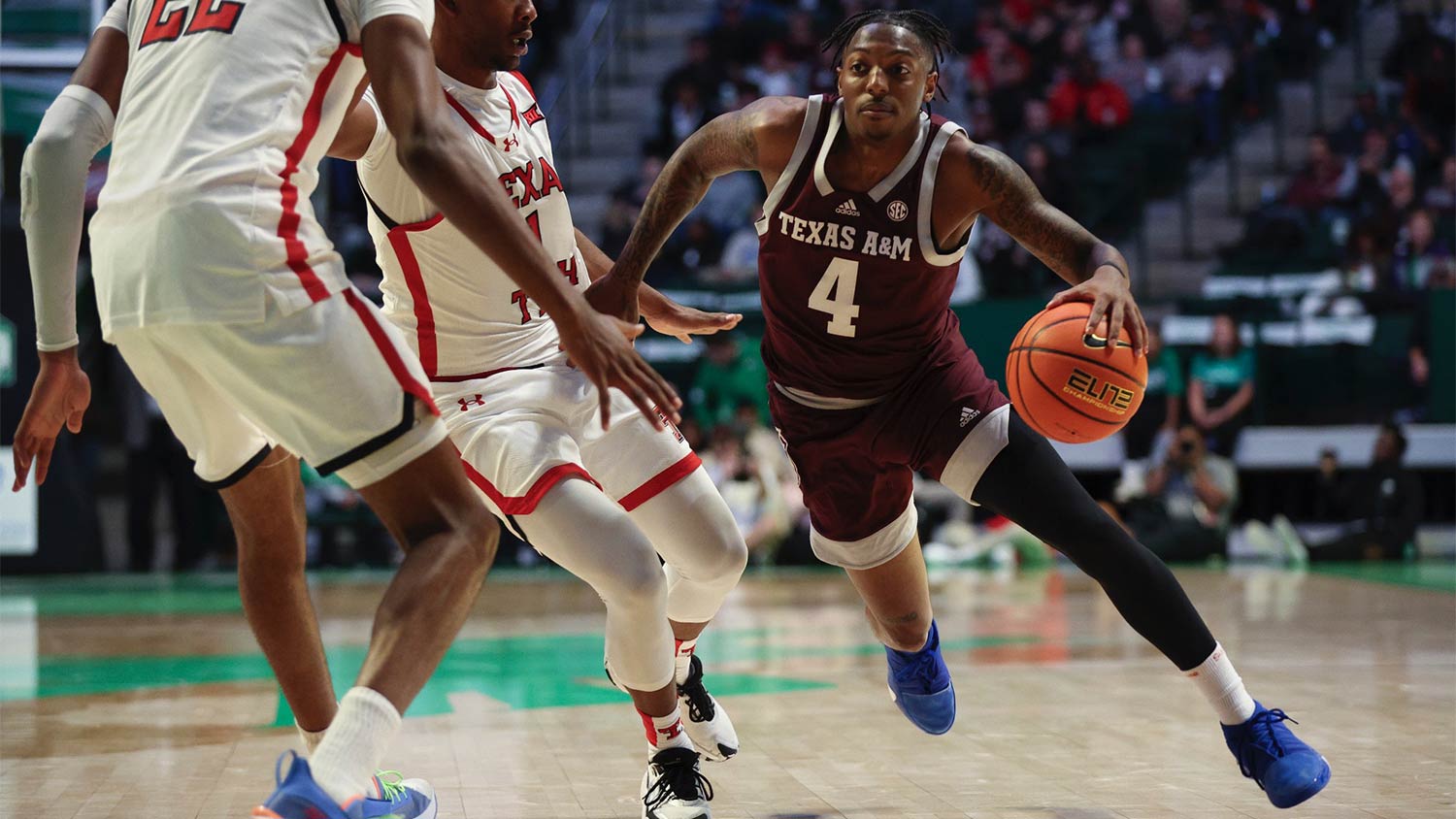 A Texas A&M basketball player dribbles past the defense toward the basket