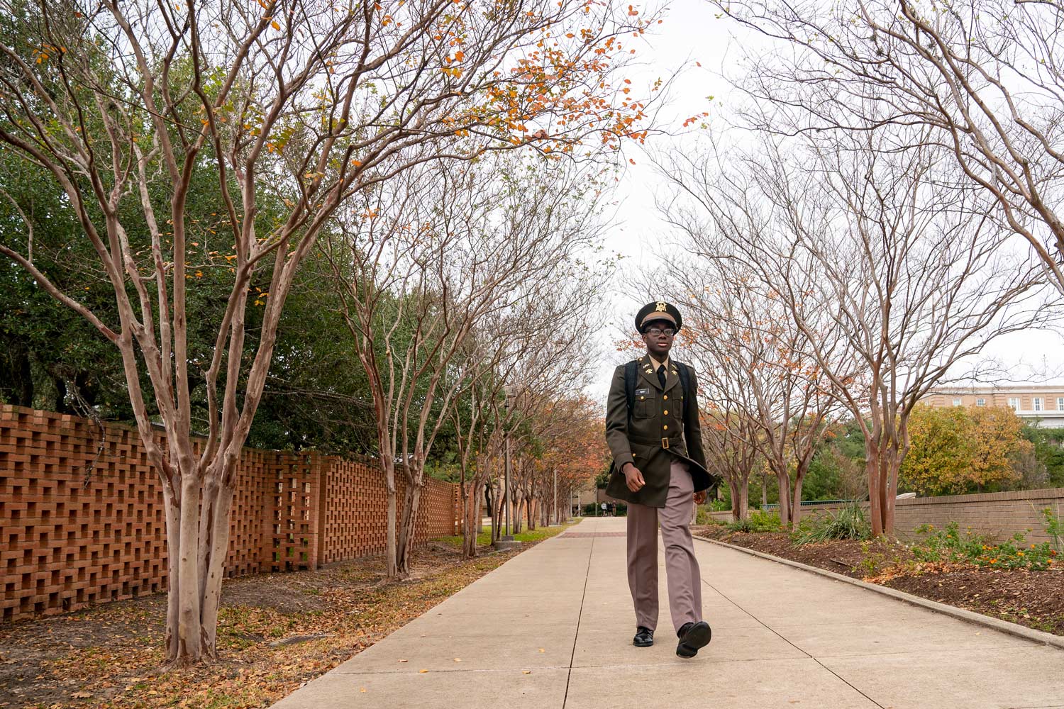 Corp of Cadet student dressed in uniform walking on campus.