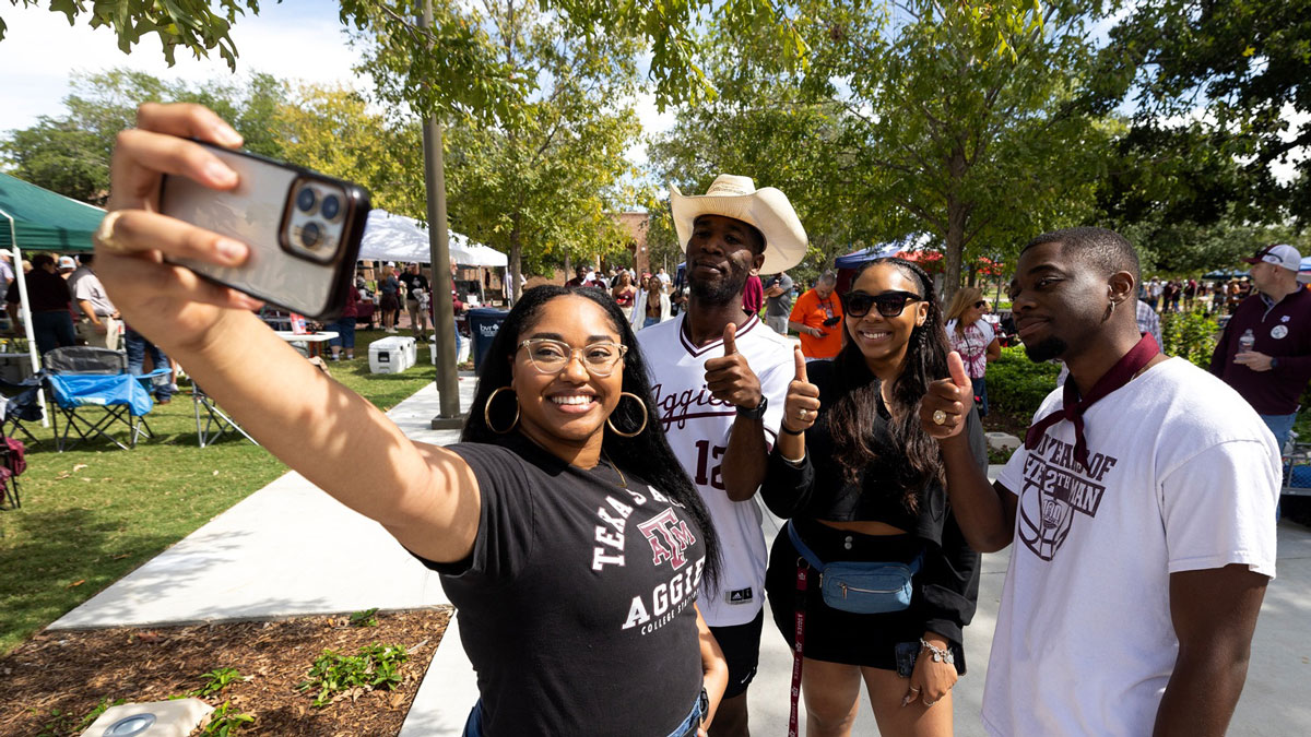 Four Texas A&M studdents pose for a selfie while tailgating at an Aggie football game