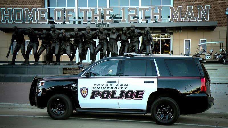 Texas A&M University police driving in front of the Kyle Field saw 'em off statue