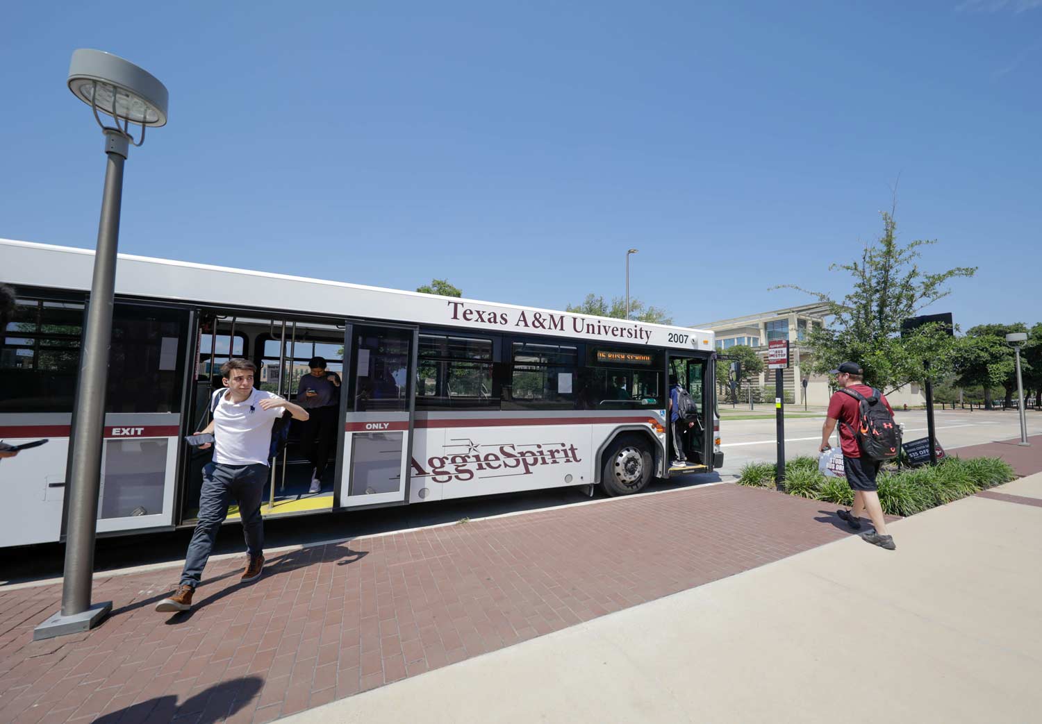 Texas A&M students getting on and off the aggie spirit bus as it stops at the MSC