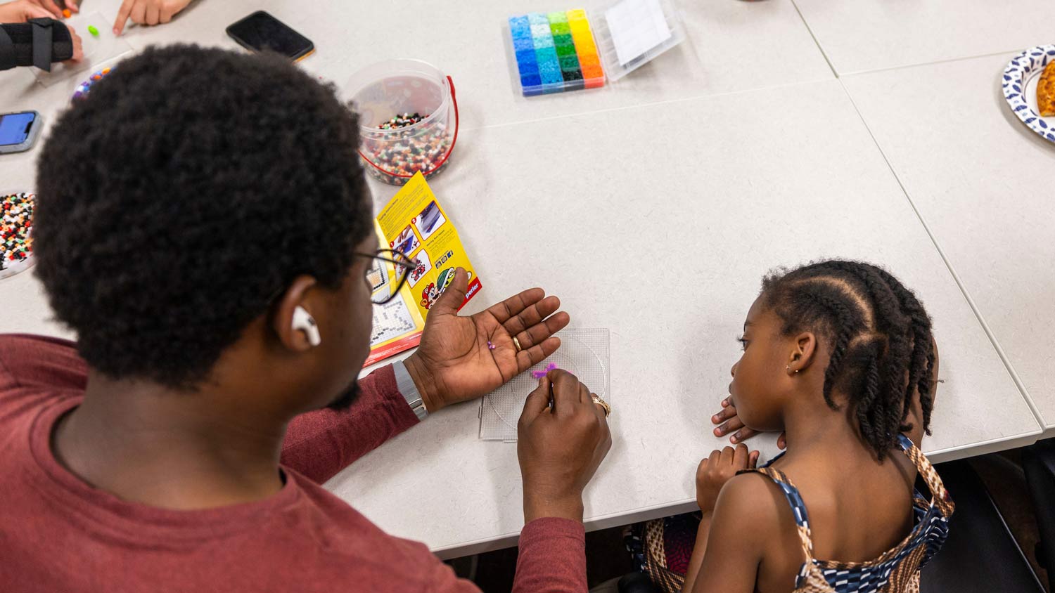 A Texas A&M student works on a craft with a child at an event
