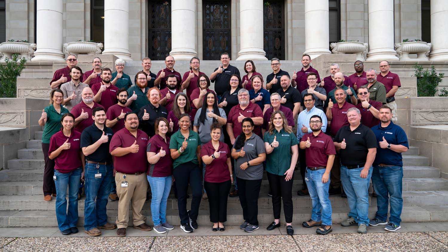 A large group of Texas A&M University staff give Gig 'Ems to the camera