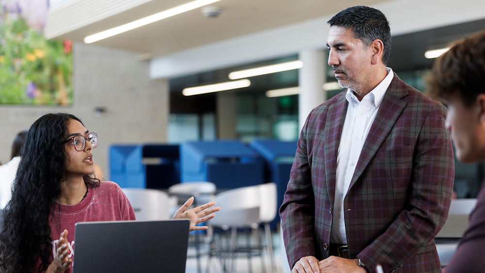 Instructor with students in a learning environment at the Mays Business School