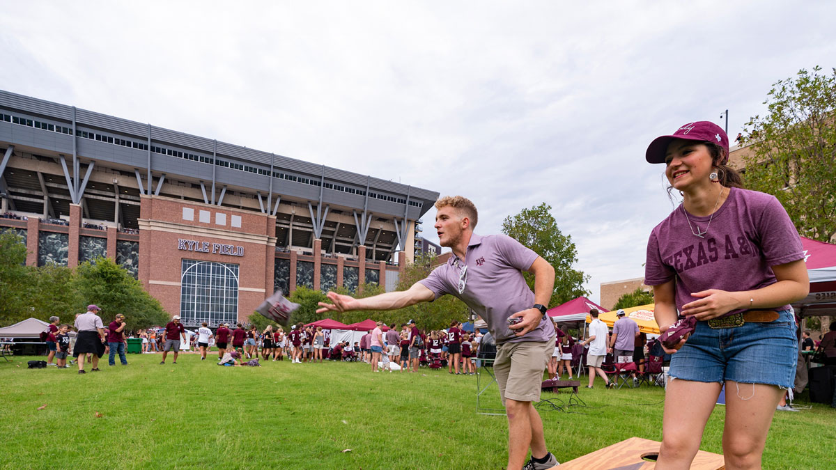Aggie students playing cornhole at an Aggie football tailgating event