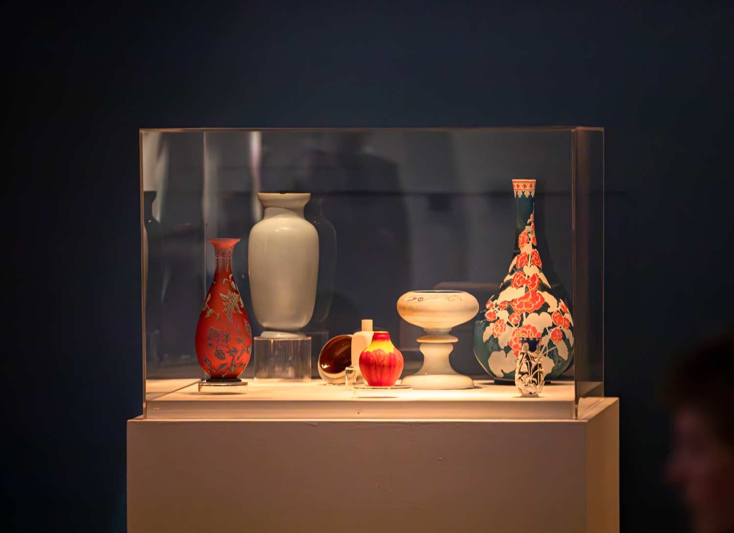 Colorful vases of various shapes and sizes in a glass display.