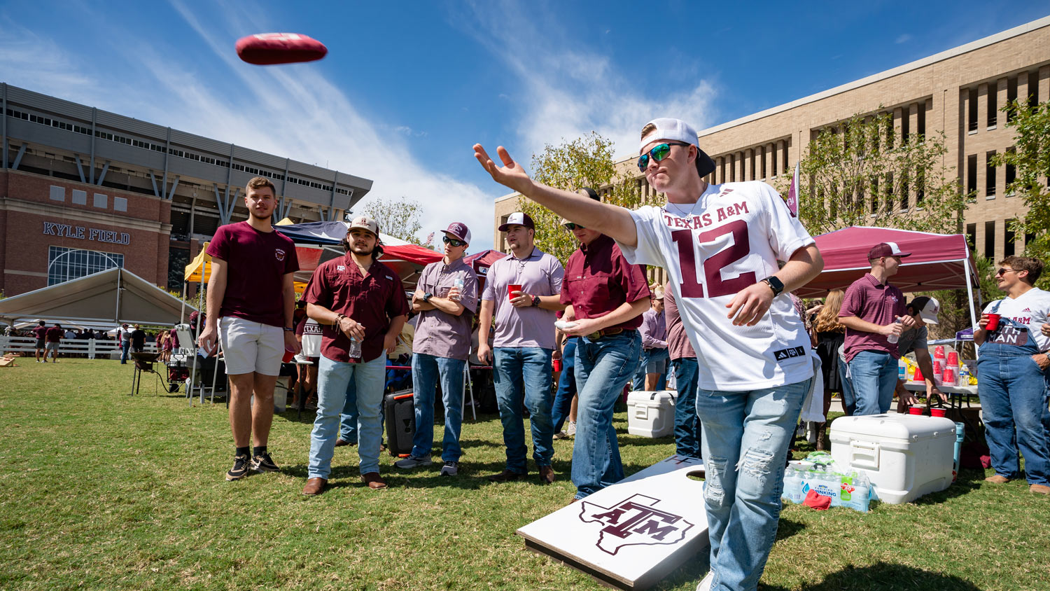 A group of students play cornhole at a Texas A&M tailgate