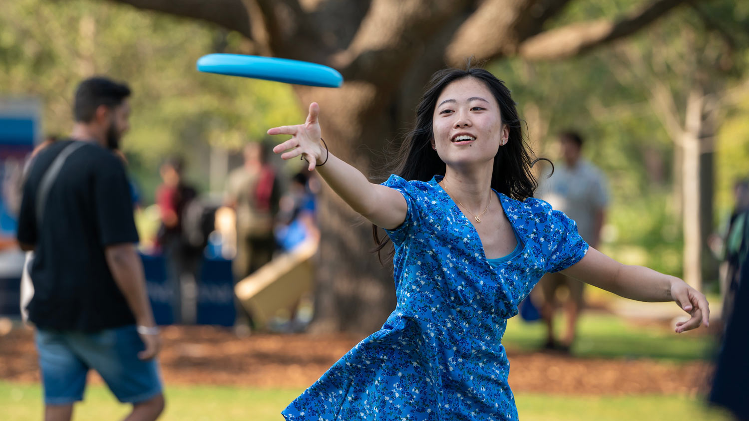 A student tosses a frisbee while at an event in Aggie Park