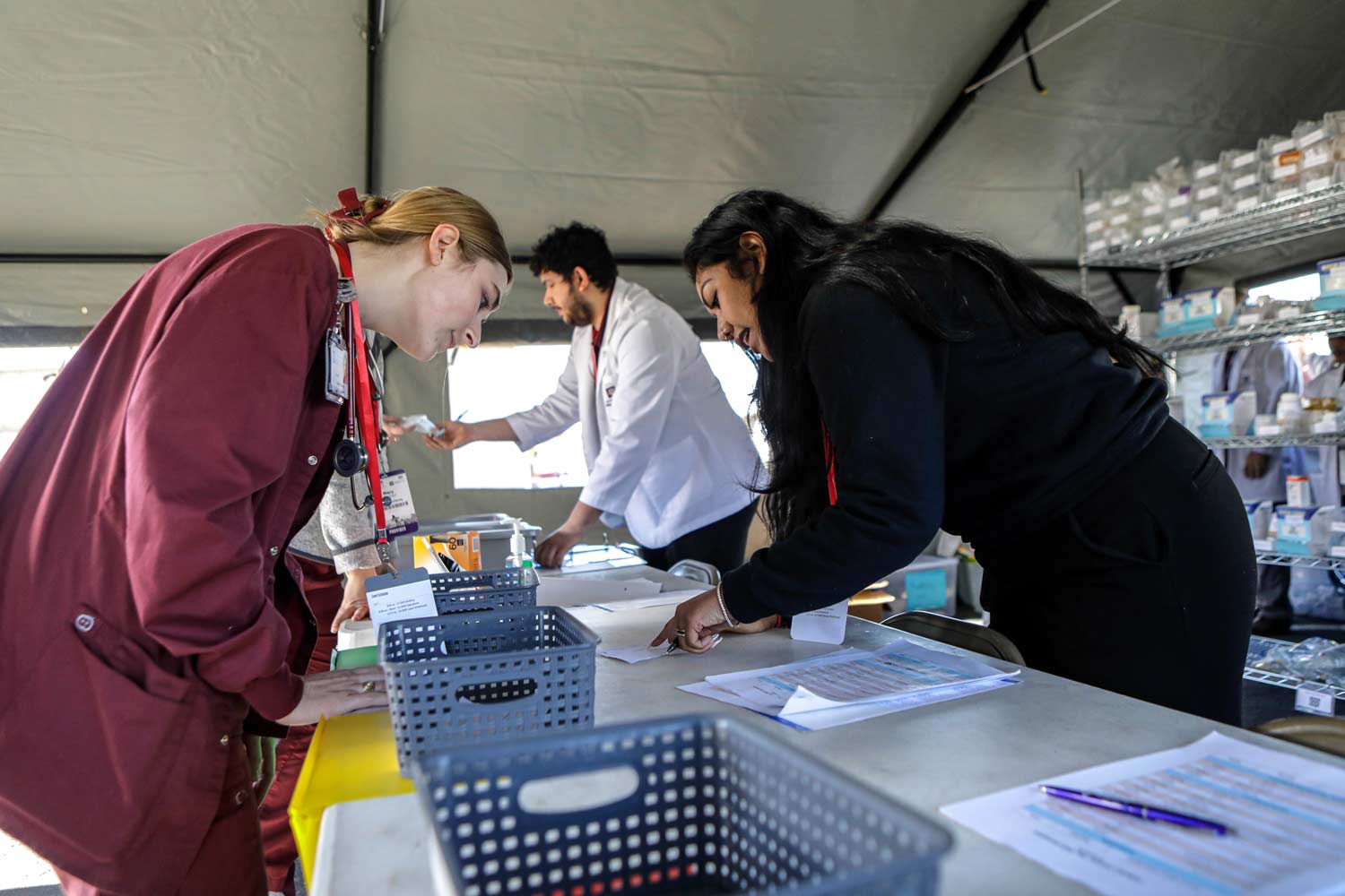 Students in Texas A&M health college programs dressed in scrubs reading a clipboard.