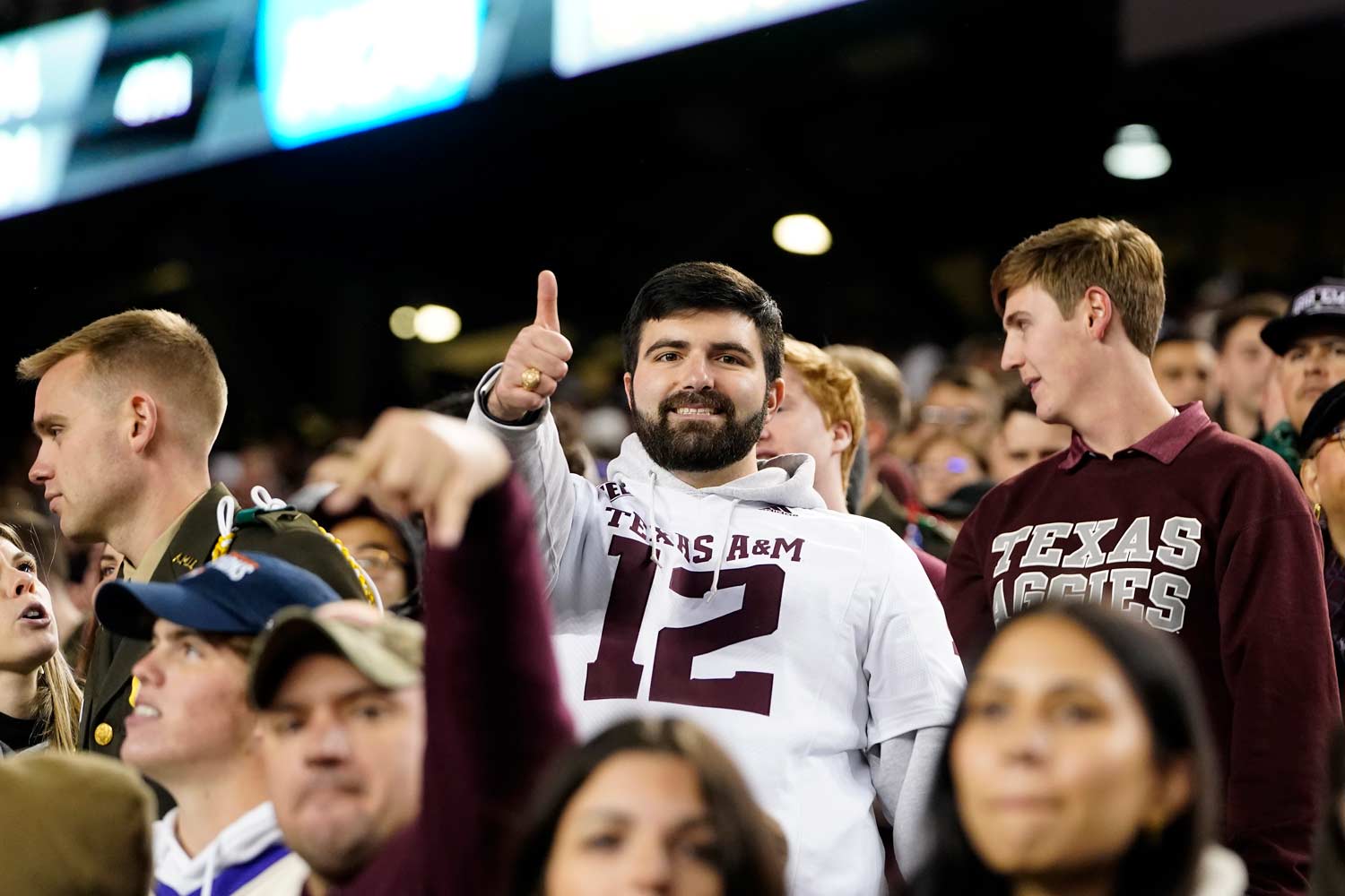 Aggie wearing a twelfth man hoodie poses for a photo during a football game