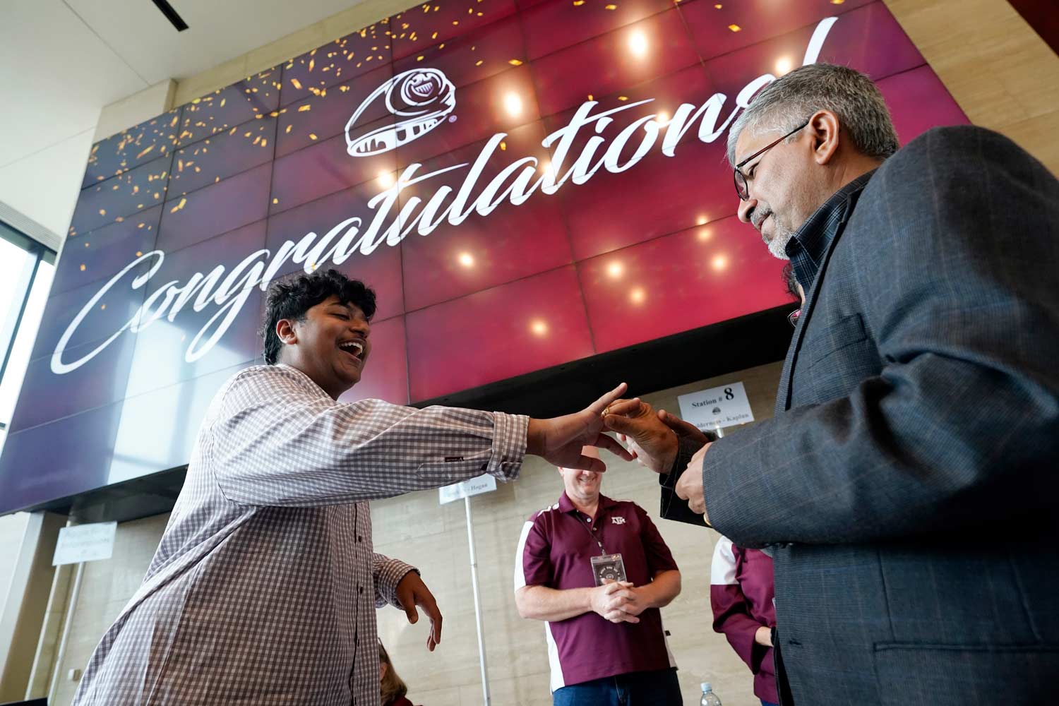 A father presents an aggie ring to his son on ring day