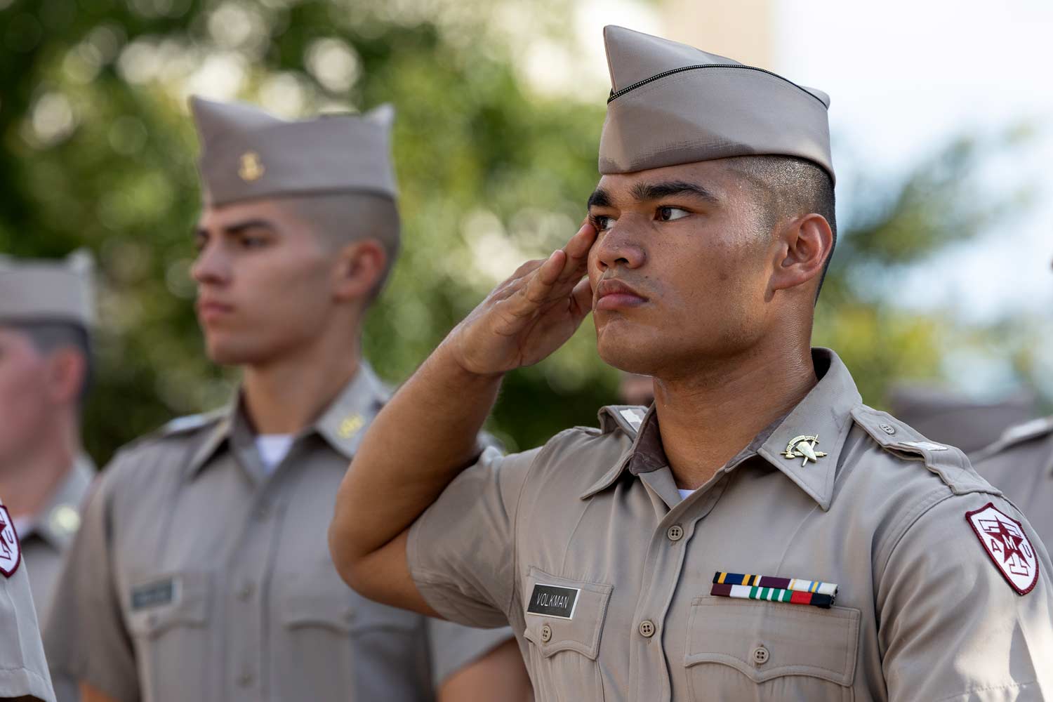 Corps of Cadets members salute during the march in at an Aggie Football game