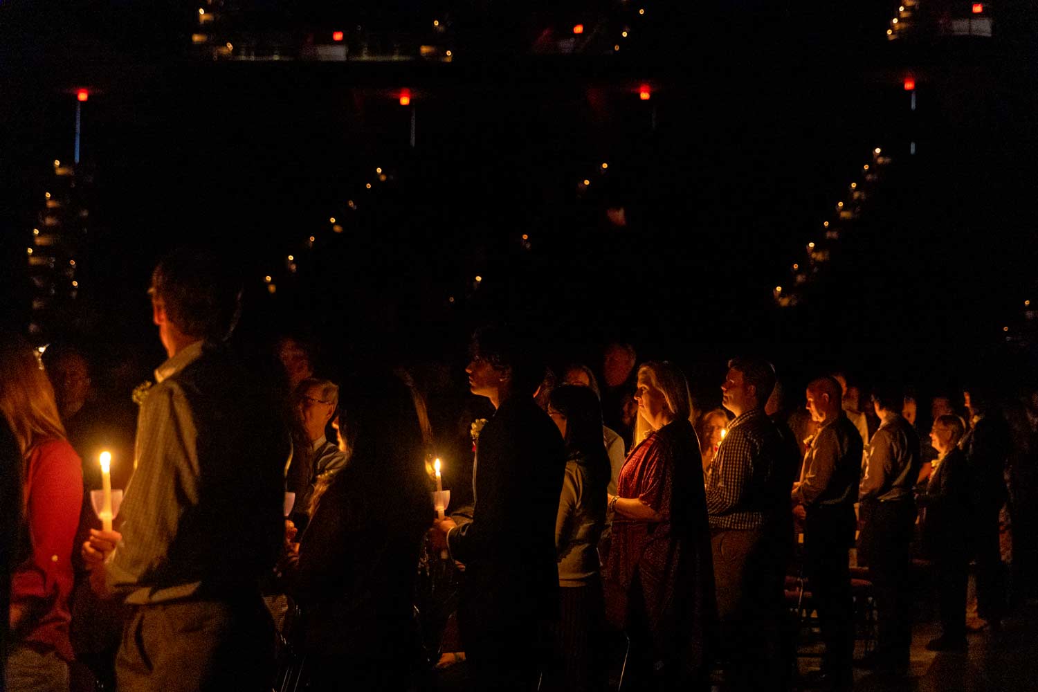 A line of Aggies stand with candles to honor the fallen at muster