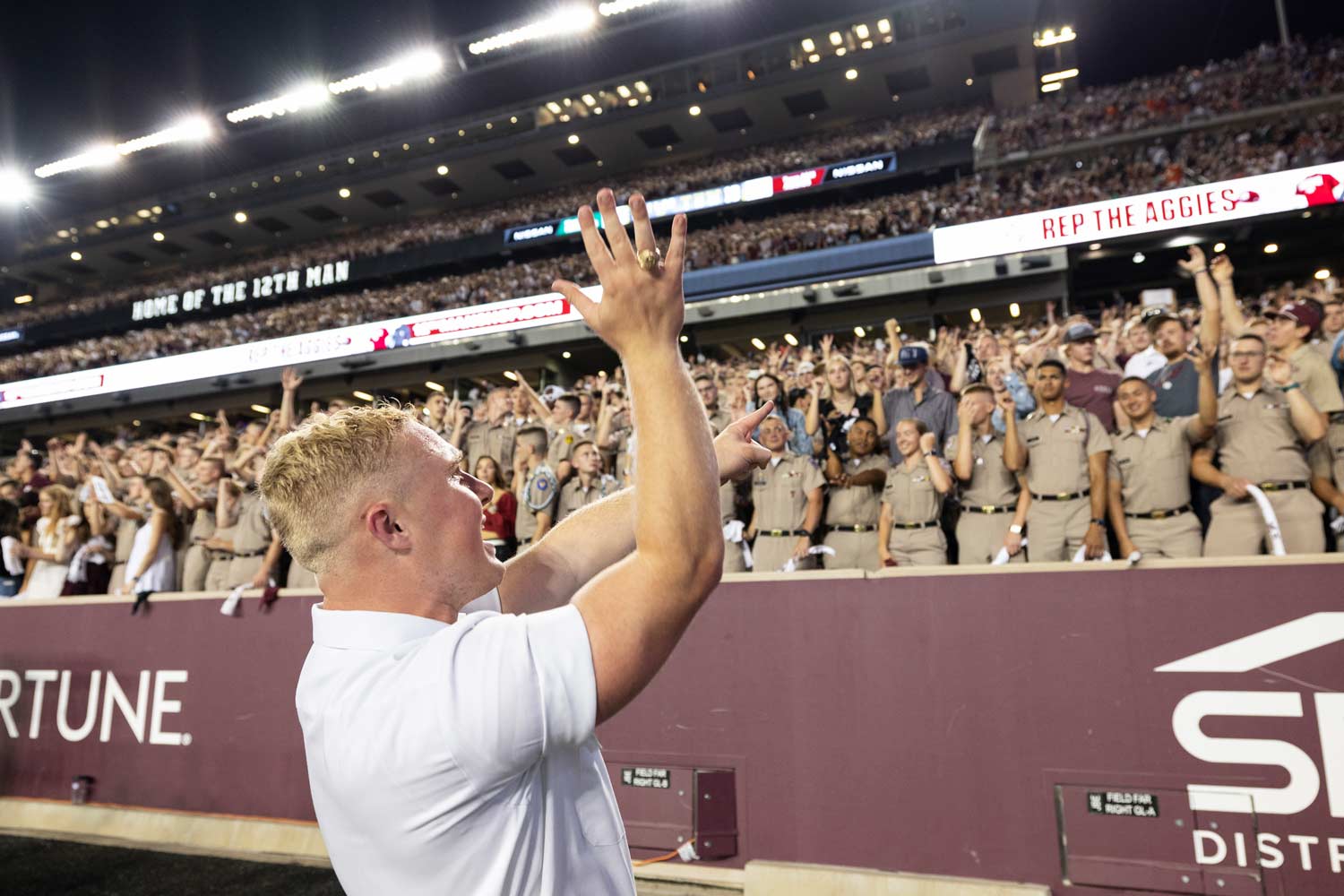 A yell leader delivers a pass back during a TAMU football game, signalling to the student section what yell to perform next