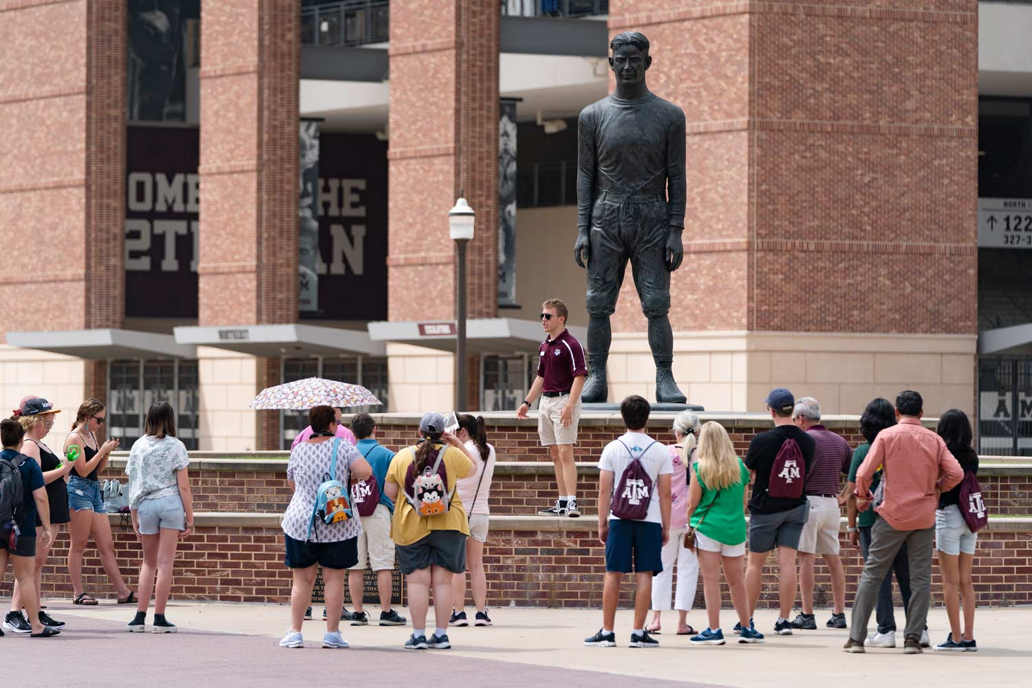 Texas A&M tour guide stands on a bench to address the crowd of prospective students