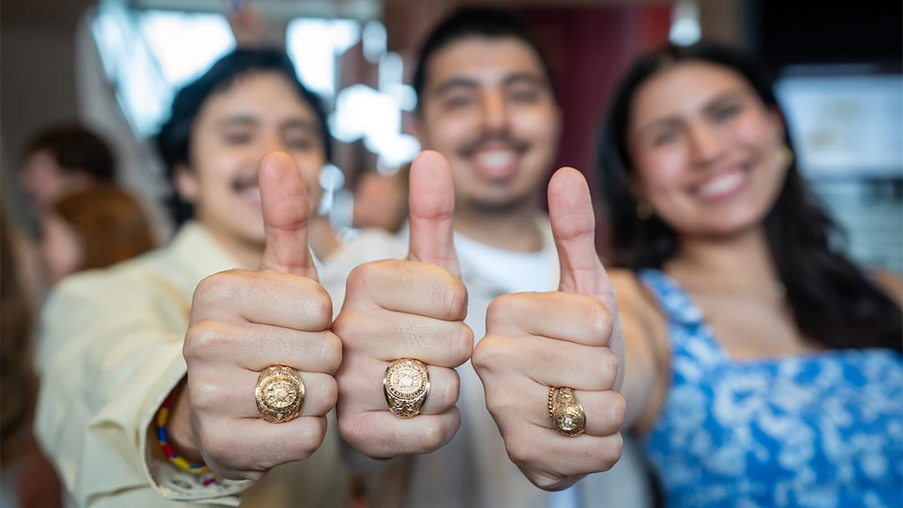 Three Aggies show off their Aggie rings in Gig 'Ems for the camera